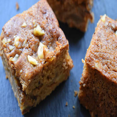 Squares of Pear and Walnut Gingerbread Traybake on a black board.